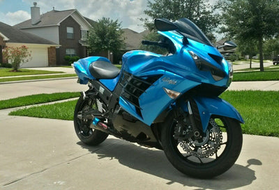 a blue motorcycle parked on a sidewalk in front of a house