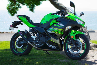 a green and black motorcycle parked in the grass