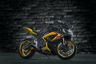 a yellow and black motorcycle parked in front of a brick wall